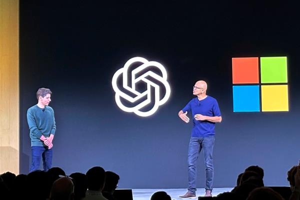 Sam Altman on stage with Satya Nadella in front of their companies' logos